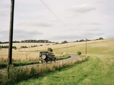 Countryside view with a jeep driving down a country lane.